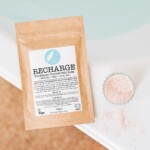 brown sachet of hot bath on edge of hot bath with loose pink bath salts
