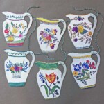 six different floral jugs hanging off twine on a grey background