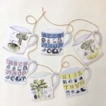 six paper mugs hanging off twine on a white background