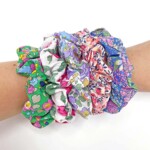 five random Liberty hair scrunchies on a wrist on a white background