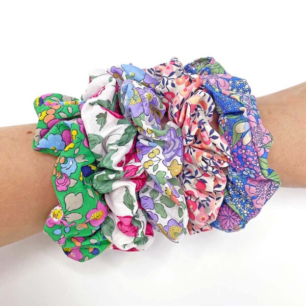 five random Liberty hair scrunchies on a wrist on a white background