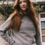 woman wearing jumper in front of a country house
