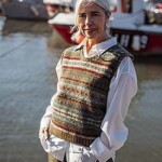 woman wearing wool vest over white shirt in a harbour scene