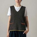 girl wearing vest top over t-shirt and trousers on a neutral background