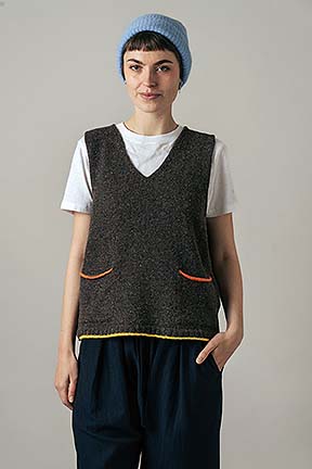 girl wearing vest top over t-shirt and trousers on a neutral background