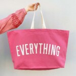 arm holding bright pink bag against white background