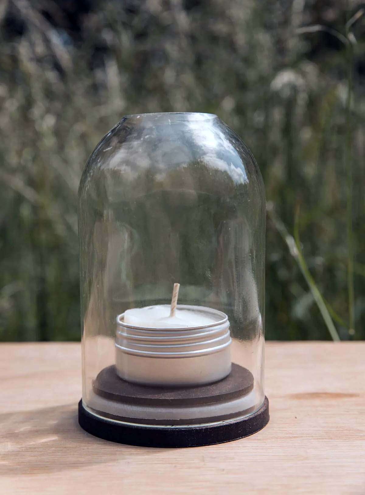 clear-glass-candle-dome clear glass dome covering tealight on wood base on table outside