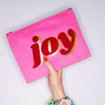 hand holding bright pink purse on white background