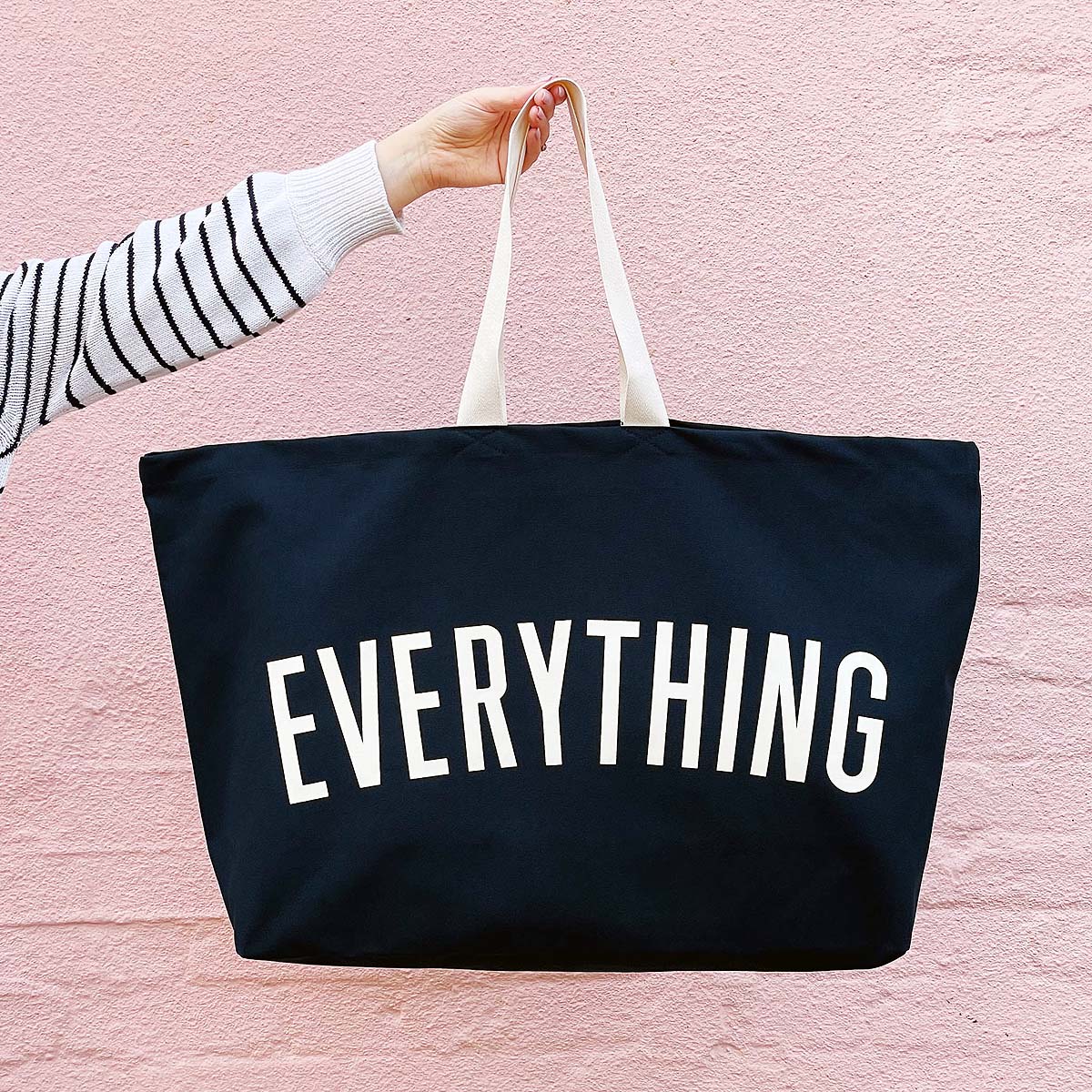 midnight-really-big-everything-bag (2) arm holding bag against a pale pink wall