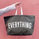 arm holding olive green bag against pink background