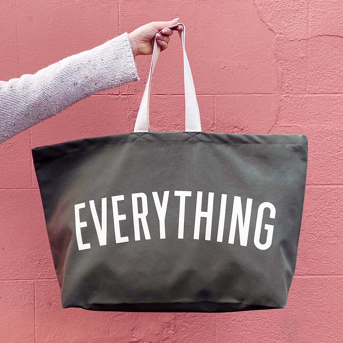 olive-green-really-big-everything-bag arm holding olive green bag against pink background