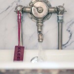 soap on road hanging from bath tap mounted on marble surround