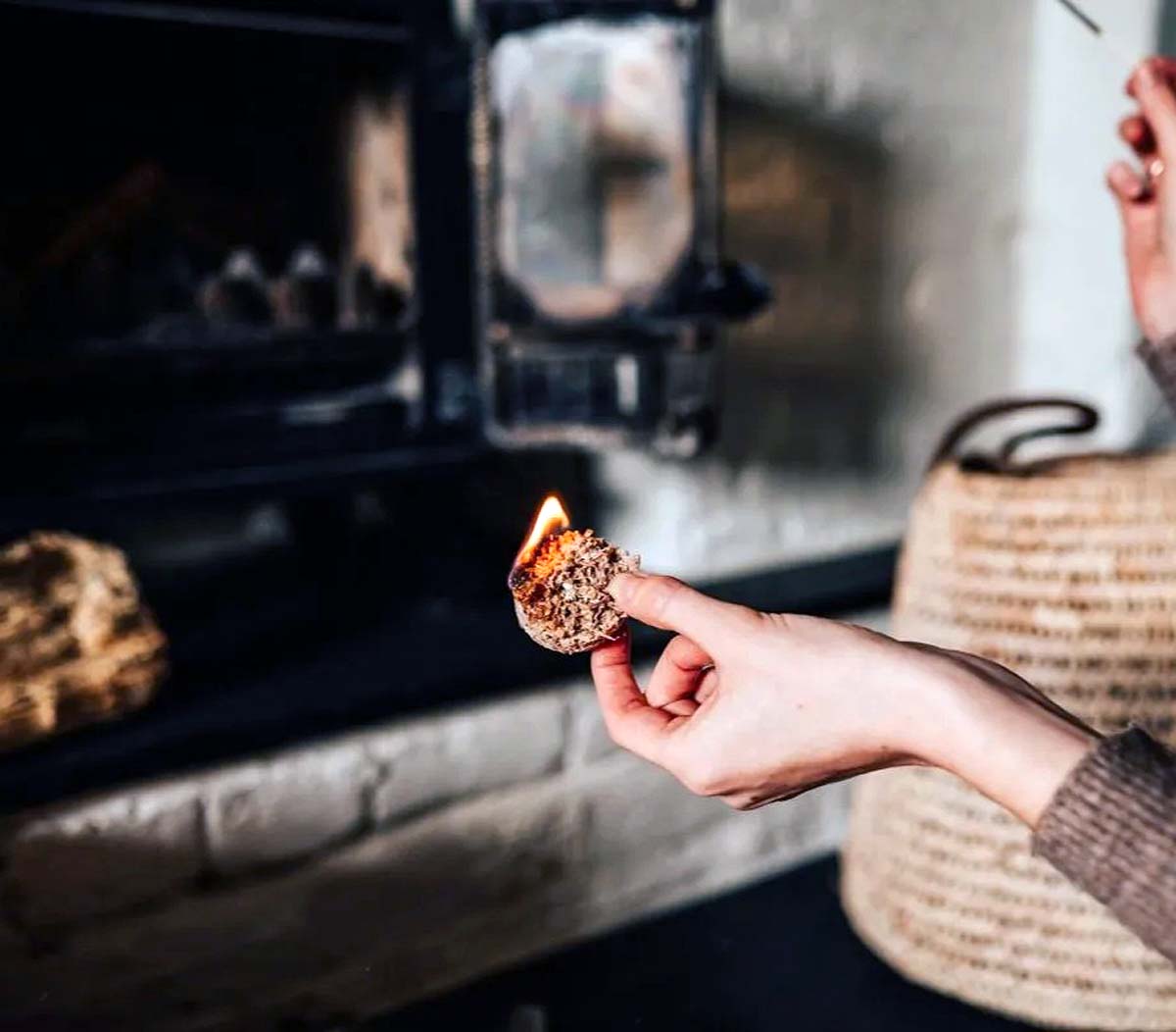 recycled-waste-wood-wax-firelighter hand holding lit firelighter in front of a wood burner