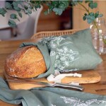 loaf of bread peeping out from bread bag on bread board with bread knife on work surface