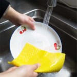 hands washing dishes with yellow cloth