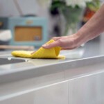 hand wiping work surface with yellow cloth