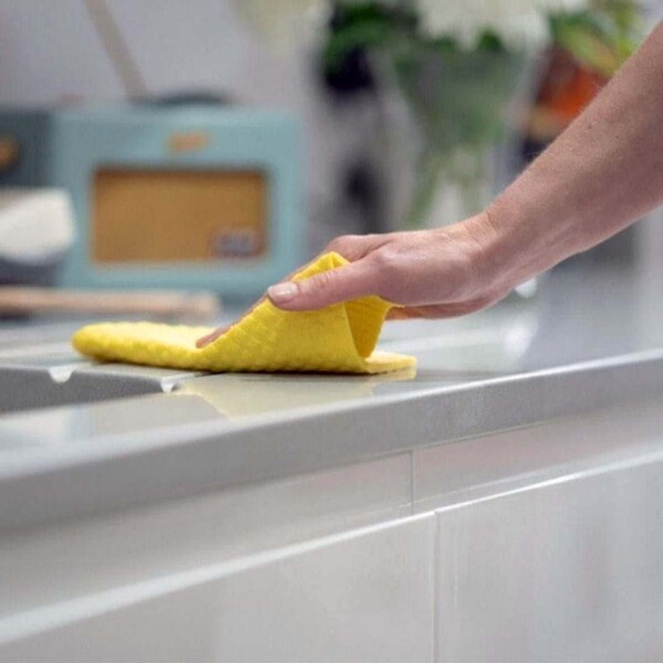 hand wiping work surface with yellow cloth